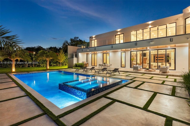 6200 Moss Ranch Rd, Pinecrest, FL 33156 - pool at night with a patio, a pool with connected hot tub, and outdoor lounge area