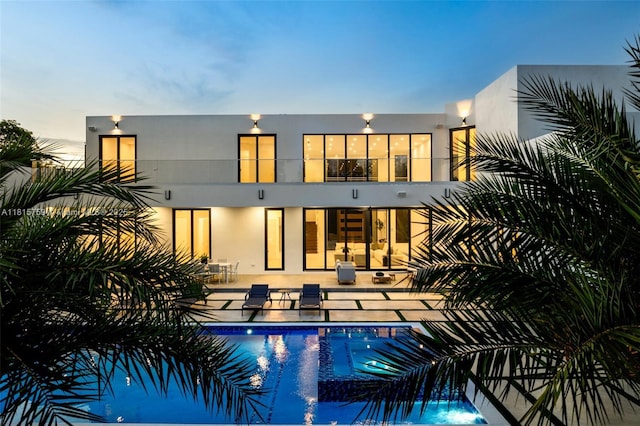 6200 Moss Ranch Rd, Pinecrest, FL 33156 - back of property featuring a balcony, a patio area, an outdoor pool, and stucco siding