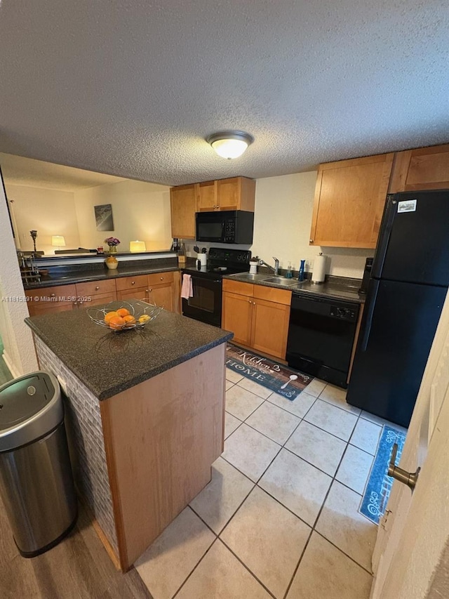 1810 NW 23rd Blvd Unit 103, Gainesville, FL 32605 - kitchen with black appliances, dark countertops, a textured ceiling, light tile patterned floors, and a kitchen island