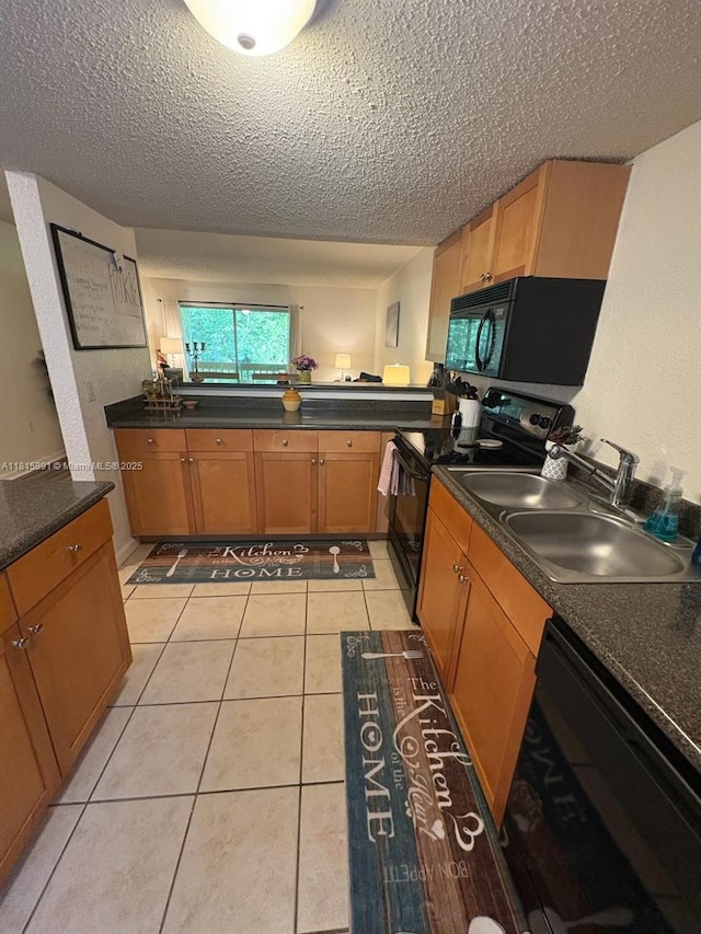 1810 NW 23rd Blvd Unit 103, Gainesville, FL 32605 - kitchen with black appliances, a textured ceiling, light tile patterned floors, dark countertops, and brown cabinetry