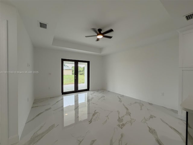 842844 Alabama Rd S, Lehigh Acres, FL 33974 - empty room featuring a ceiling fan, light marble finish flooring, a tray ceiling, and french doors