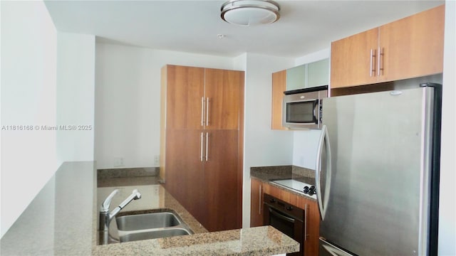 300 S Biscayne Blvd Unit 2705, Miami, FL 33131 - kitchen with black appliances, brown cabinetry, a sink, and light stone counters