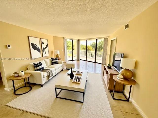 1000 Quayside Te Unit 410, Miami, FL 33138 - living area featuring a wall of windows, light tile patterned flooring, and a textured ceiling