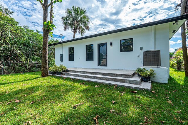 2725 NW 7th St, Fort Lauderdale, FL 33311 - rear view of house with cooling unit, a yard, and stucco siding