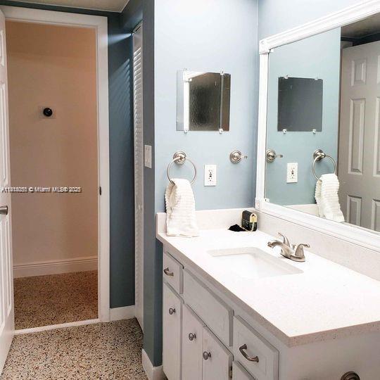 482 NE 8th Ave, Deerfield Beach, FL 33441 - bathroom with baseboards, speckled floor, and vanity