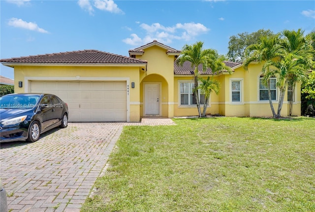4441 SW Savona Blvd, Port St Lucie, FL 34953 - mediterranean / spanish home featuring a garage, a front lawn, stucco siding, and decorative driveway