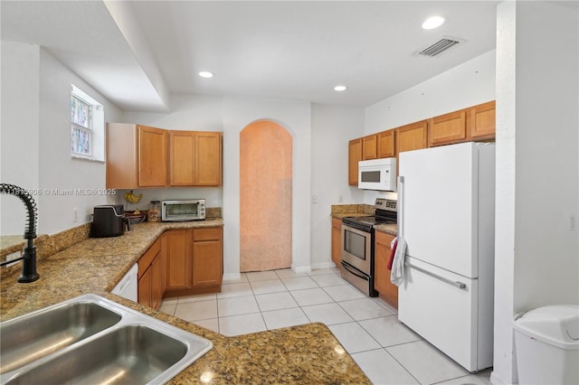 4441 SW Savona Blvd, Port St Lucie, FL 34953 - kitchen with white appliances, a sink, recessed lighting, arched walkways, and brown cabinets