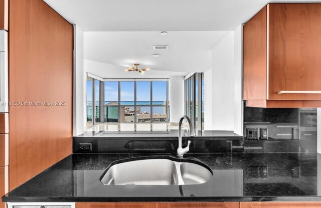 1331 Brickell Bay Dr Unit 1808, Miami, FL 33131 - kitchen featuring a sink, brown cabinets, dark stone counters, and a chandelier