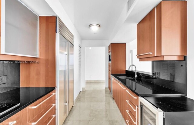 1331 Brickell Bay Dr Unit 1808, Miami, FL 33131 - kitchen featuring a sink, brown cabinets, built in refrigerator, and dark stone counters