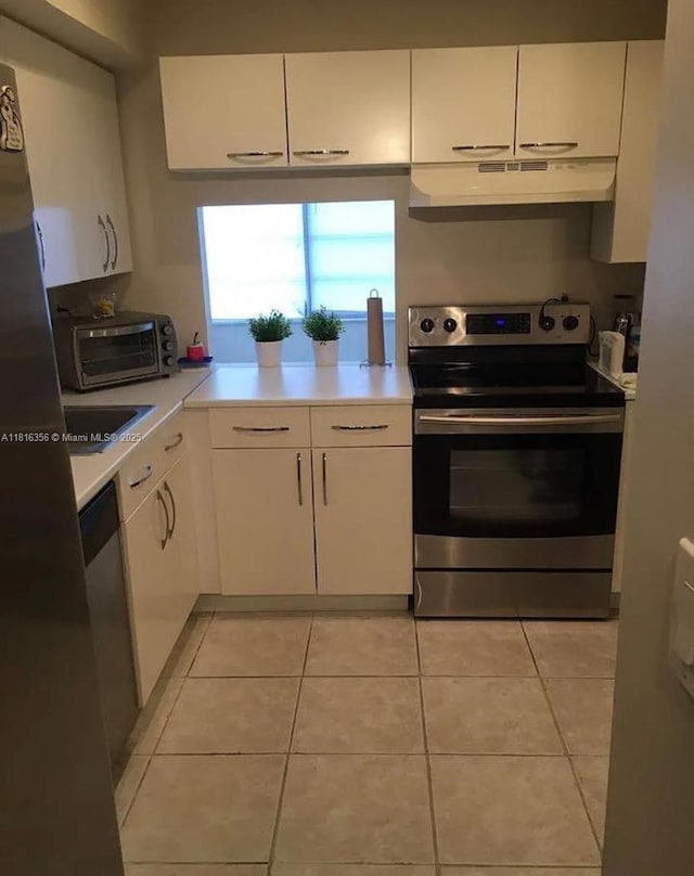 250 180th Dr Unit 159, Sunny Isles Beach, FL 33160 - kitchen with stainless steel appliances, under cabinet range hood, light countertops, white cabinets, and light tile patterned floors