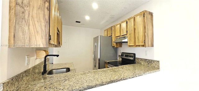kitchen with appliances with stainless steel finishes, a sink, under cabinet range hood, a textured ceiling, and light stone countertops