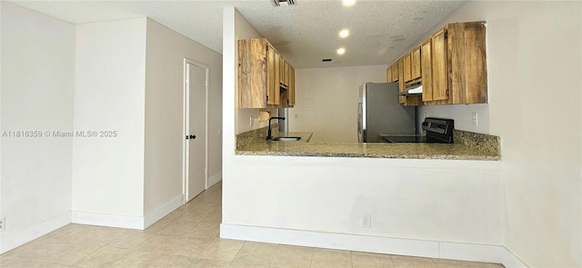 kitchen with electric range, a sink, freestanding refrigerator, under cabinet range hood, and brown cabinets