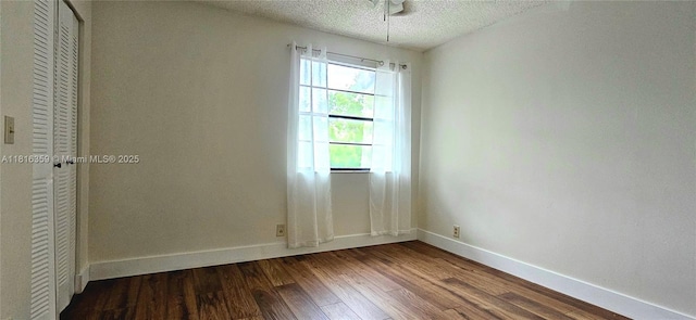 unfurnished room featuring dark wood-style floors, baseboards, and a textured ceiling