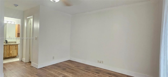 unfurnished bedroom featuring light wood-style flooring, baseboards, and connected bathroom