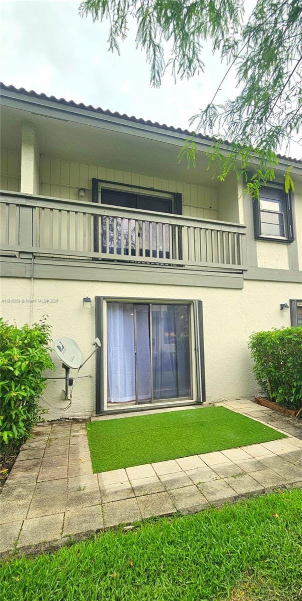 rear view of property featuring a balcony and stucco siding