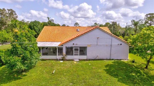 17084 N 33rd Rd N, Loxahatchee, FL 33470 - rear view of house featuring a sunroom, a lawn, a tiled roof, and stucco siding