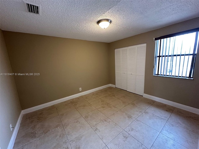 2541 NW 56th Ave Unit 3-19, Lauderhill, FL 33313 - unfurnished bedroom featuring a closet, light tile patterned floors, a textured ceiling, and baseboards