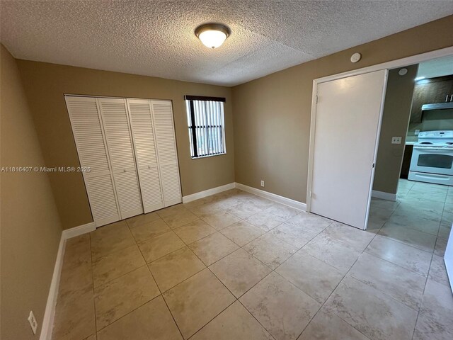 2541 NW 56th Ave Unit 3-19, Lauderhill, FL 33313 - unfurnished bedroom featuring a closet, a textured ceiling, light tile patterned floors, and baseboards