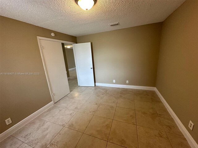 2541 NW 56th Ave Unit 3-19, Lauderhill, FL 33313 - unfurnished bedroom with light tile patterned floors, a textured ceiling, and baseboards