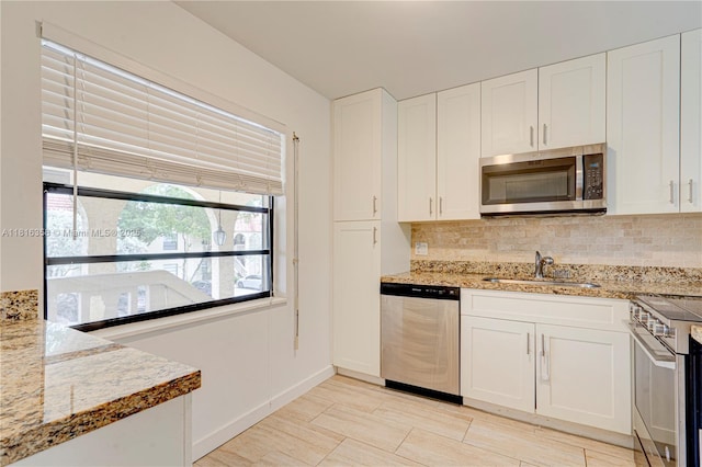 136 S Cypress Rd Unit 323, Pompano Beach, FL 33060 - kitchen featuring appliances with stainless steel finishes, a sink, decorative backsplash, and white cabinets