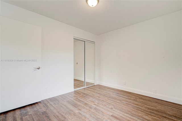 136 S Cypress Rd Unit 323, Pompano Beach, FL 33060 - unfurnished bedroom with wood finished floors, baseboards, a closet, and a textured ceiling
