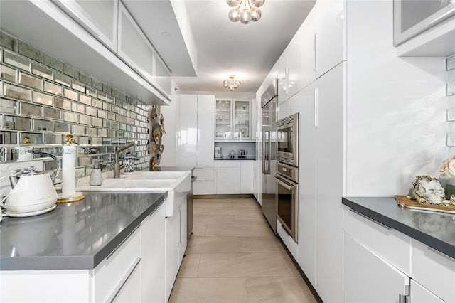 1800 S Ocean Dr Unit 2208, Hallandale Beach, FL 33009 - kitchen with stainless steel appliances, white cabinets, light tile patterned flooring, glass insert cabinets, and dark countertops