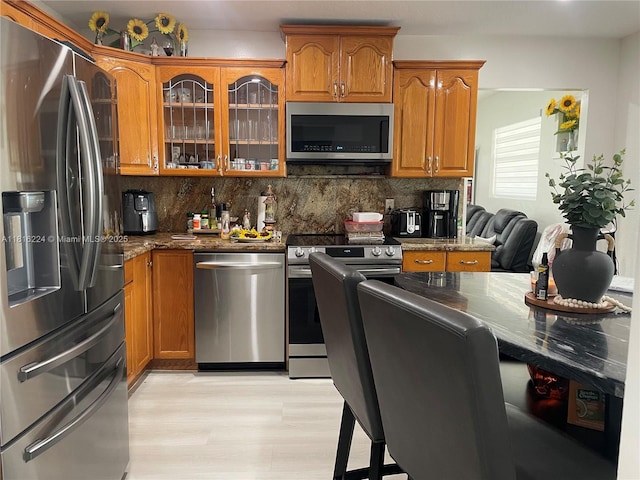 14511 SW 294th St, Homestead, FL 33033 - kitchen with stainless steel appliances, brown cabinetry, dark stone counters, backsplash, and glass insert cabinets