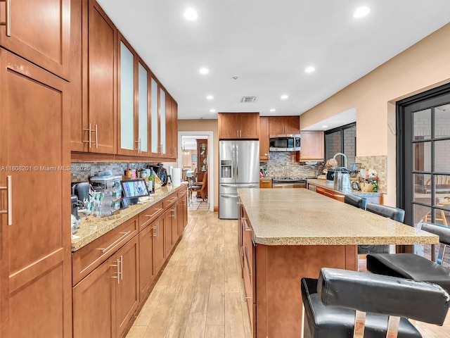 3121 N 52nd Ave, Hollywood, FL 33021 - kitchen with appliances with stainless steel finishes, light wood finished floors, a kitchen breakfast bar, backsplash, and recessed lighting