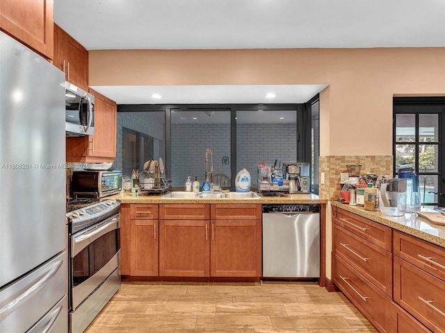 3121 N 52nd Ave, Hollywood, FL 33021 - kitchen featuring appliances with stainless steel finishes, brown cabinetry, decorative backsplash, a sink, and light stone countertops