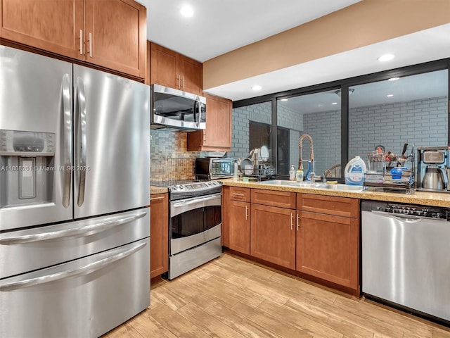 3121 N 52nd Ave, Hollywood, FL 33021 - kitchen featuring appliances with stainless steel finishes, brown cabinetry, light wood-style floors, a sink, and light countertops