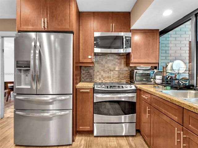3121 N 52nd Ave, Hollywood, FL 33021 - kitchen featuring stainless steel appliances, brown cabinetry, light wood-style floors, and recessed lighting
