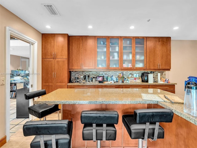 3121 N 52nd Ave, Hollywood, FL 33021 - kitchen featuring brown cabinets, a kitchen breakfast bar, glass insert cabinets, decorative backsplash, and recessed lighting