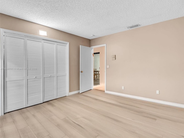3121 N 52nd Ave, Hollywood, FL 33021 - unfurnished bedroom featuring light wood finished floors, a textured ceiling, baseboards, and a closet