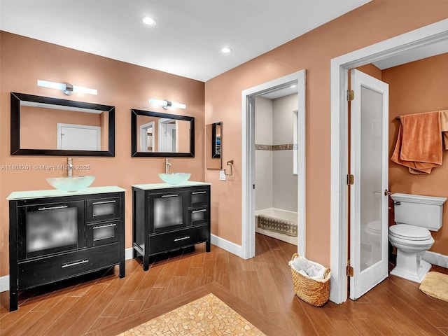 3121 N 52nd Ave, Hollywood, FL 33021 - full bathroom with baseboards, toilet, wood finished floors, two vanities, and recessed lighting