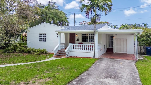 1110 Falcon Ave, Miami Springs, FL 33166 - view of front facade featuring covered porch, driveway, a front lawn, stucco siding, and an attached carport