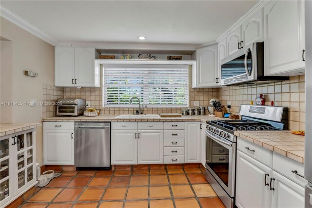 1110 Falcon Ave, Miami Springs, FL 33166 - kitchen featuring appliances with stainless steel finishes, a sink, tile countertops, white cabinetry, and crown molding