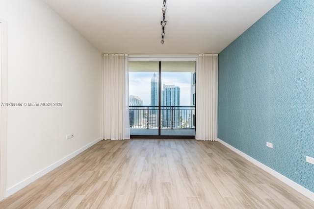 999 1st Ave Unit 2707, Miami, FL 33130 - unfurnished room with floor to ceiling windows, wood finished floors, an accent wall, baseboards, and wallpapered walls