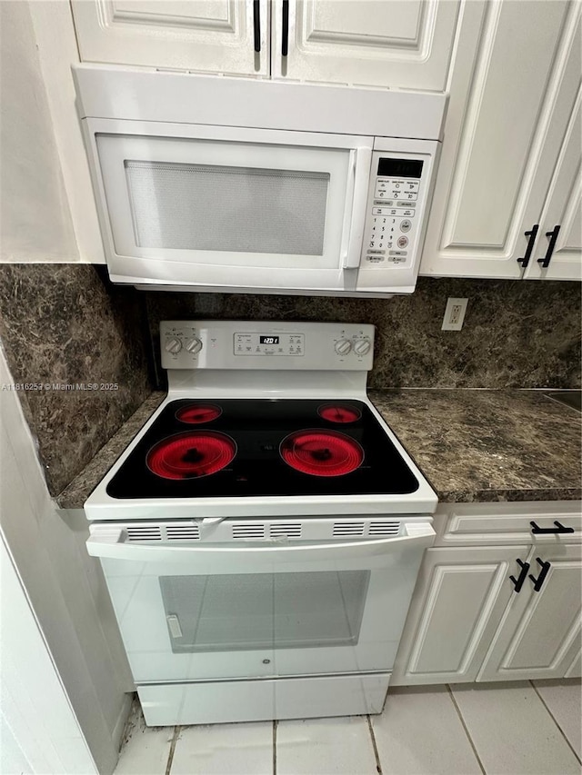 677 SW 9th Ave Unit 309, Miami, FL 33130 - kitchen view of white appliances, white cabinetry, backsplash, and dark stone counters