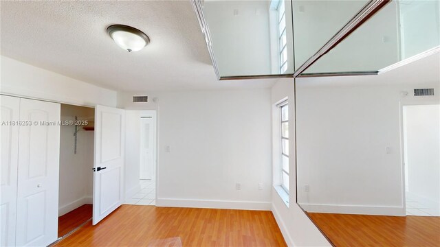 677 SW 9th Ave Unit 309, Miami, FL 33130 - unfurnished bedroom featuring light wood-type flooring, a closet, baseboards, and a textured ceiling