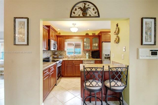 6710 SW 33rd St, Miami, FL 33155 - kitchen featuring appliances with stainless steel finishes, a sink, a kitchen breakfast bar, decorative backsplash, and a peninsula