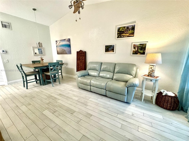 729 NW 47th St, Deerfield Beach, FL 33064 - living room with ceiling fan, light wood-style floors, baseboards, vaulted ceiling, and a textured wall