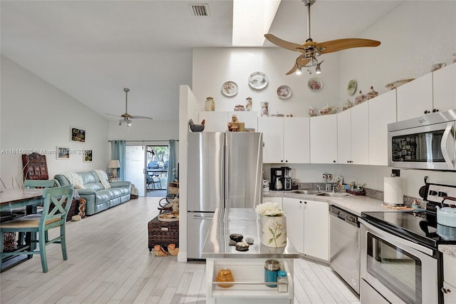 729 NW 47th St, Deerfield Beach, FL 33064 - kitchen with stainless steel appliances, ceiling fan, a sink, white cabinetry, and high vaulted ceiling
