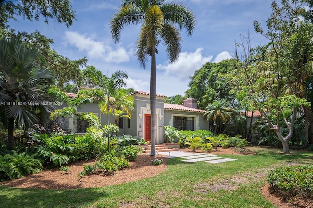 492 NE 55th St, Miami, FL 33137 - mediterranean / spanish-style home with a tile roof, stucco siding, a front yard, and a chimney