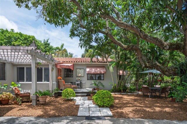 492 NE 55th St, Miami, FL 33137 - back of house with stucco siding, a tile roof, a pergola, and a patio