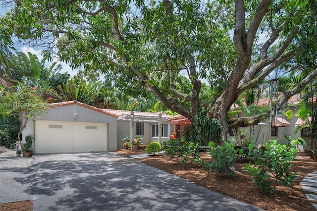 492 NE 55th St, Miami, FL 33137 - view of front of house with driveway, an attached garage, a tiled roof, and stucco siding
