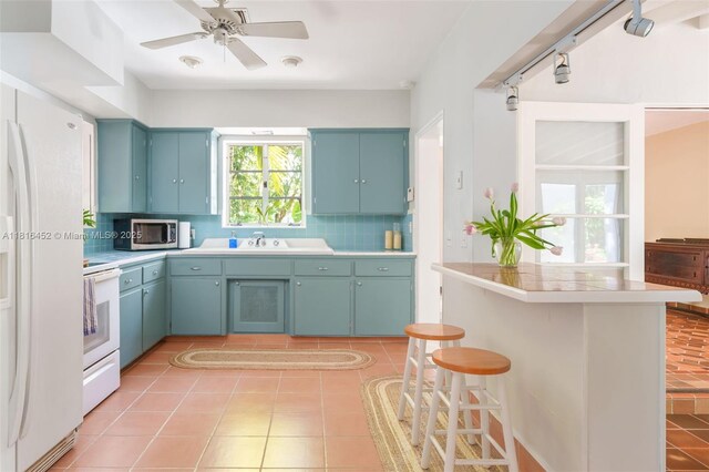 492 NE 55th St, Miami, FL 33137 - kitchen with white appliances, tasteful backsplash, light countertops, a kitchen breakfast bar, and light tile patterned floors