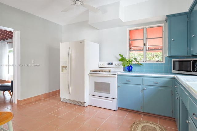 492 NE 55th St, Miami, FL 33137 - kitchen featuring white appliances, blue cabinets, ceiling fan, tile countertops, and light tile patterned floors