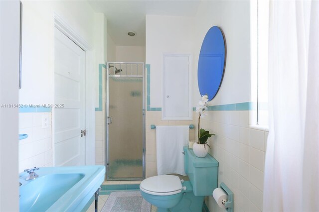492 NE 55th St, Miami, FL 33137 - full bath with tile walls, a shower stall, toilet, tile patterned floors, and a wainscoted wall