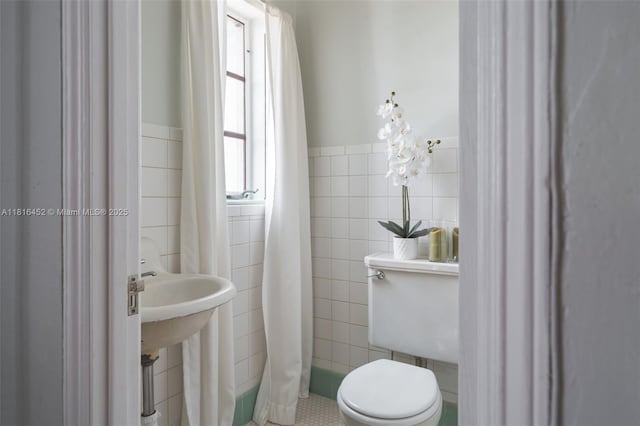 492 NE 55th St, Miami, FL 33137 - bathroom featuring tile walls, toilet, wainscoting, tile patterned floors, and a sink