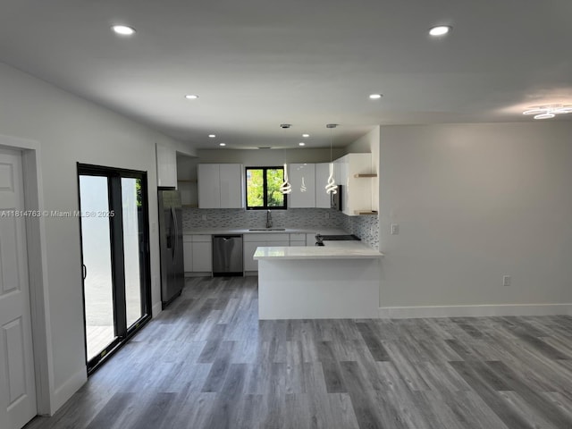 2160 NW 30th St, Miami, FL 33142 - kitchen featuring appliances with stainless steel finishes, a peninsula, light countertops, wood finished floors, and tasteful backsplash